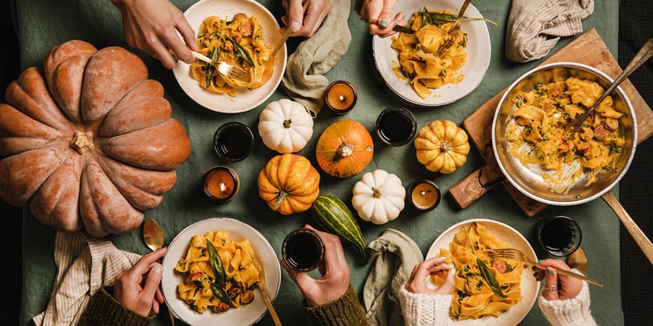 Four friends share a tabletop meal featuring winter squash varieties.